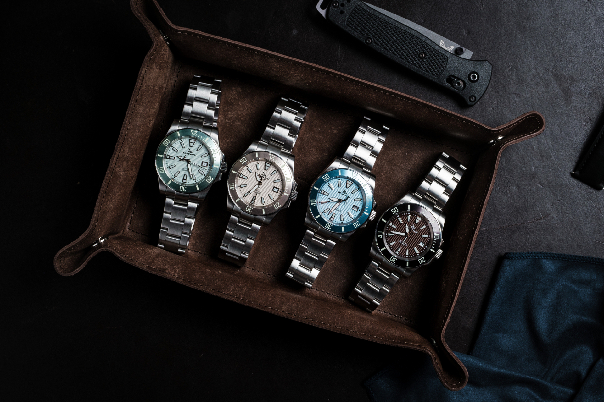 Four stainless steel NSB Watch Canaveral timepieces arranged in a leather watch roll